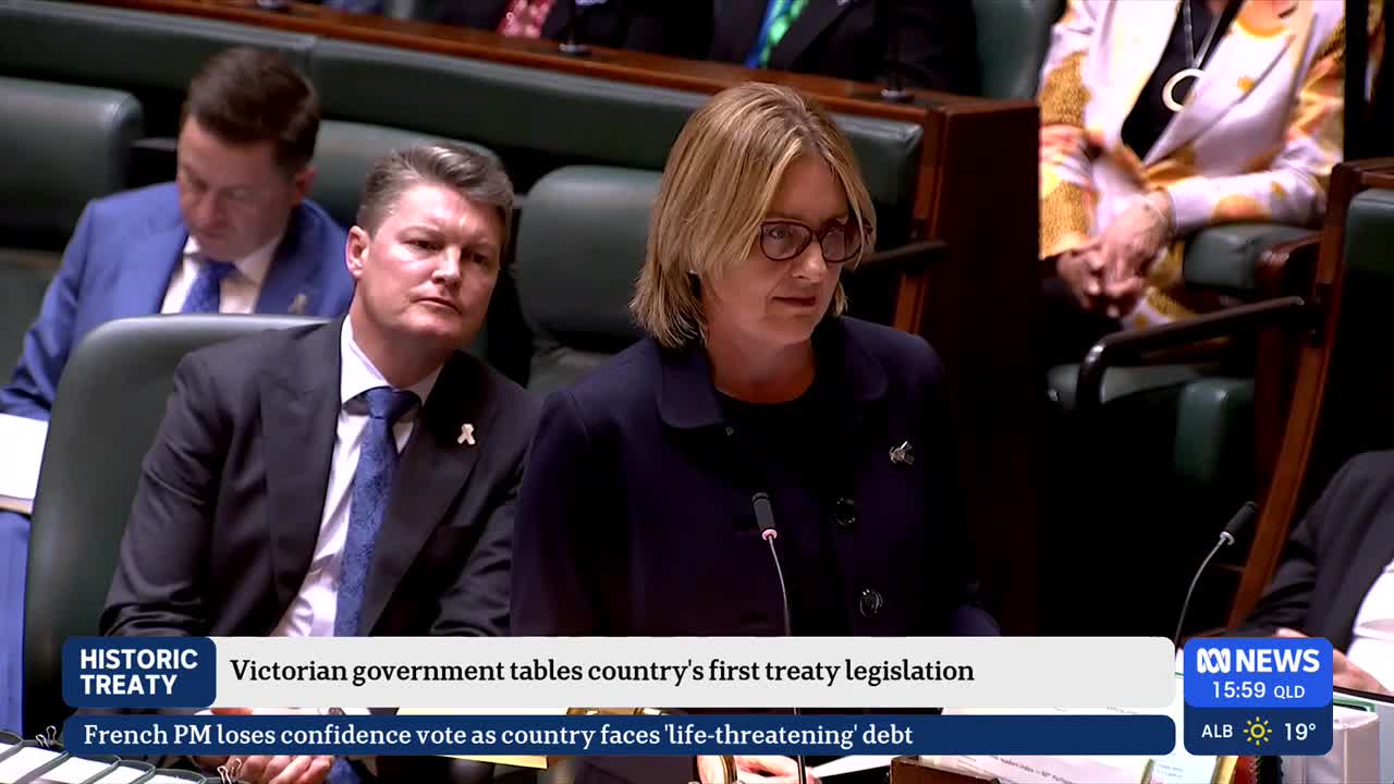 A woman with glasses speaks at a lectern, while two men in suits observe from their seats. The ABC News logo and a news ticker are visible at the bottom of the screen.
