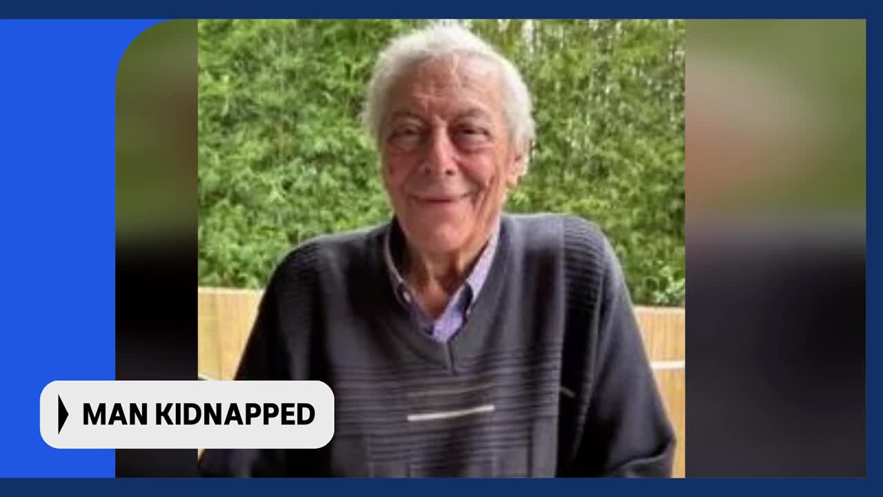 A man with white hair smiles, wearing a dark sweater over a collared shirt. A white banner at the bottom left reads "MAN KIDNAPPED."