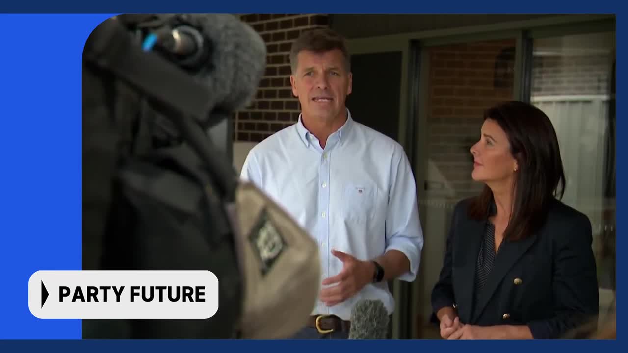 A man in a light blue shirt speaks into a microphone, while a woman in a dark blazer stands beside him. A graphic overlay reads "PARTY FUTURE."