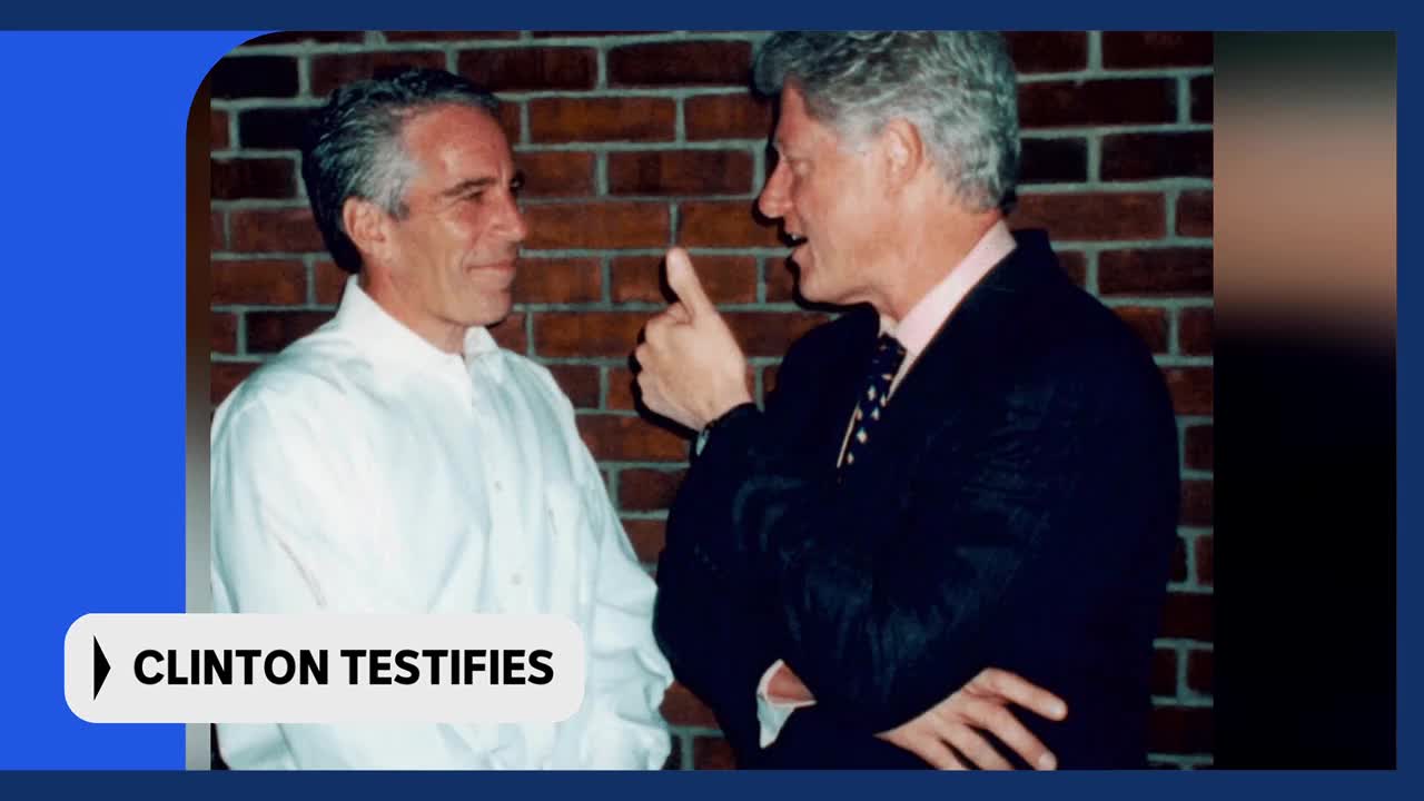 Two men stand talking in front of a brick wall. One man, wearing a white shirt, looks towards the other. The second man, in a dark suit and tie, gestures with his thumb raised. Two men stand talking in front of a brick wall. One man, wearing a white shirt, looks towards the other. The second man, in a dark suit and tie, gestures with his thumb raised.