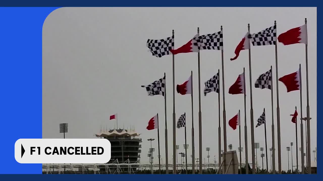 The wind whips the checkered flags and the red and white flags of Bahrain against a grey sky. The grandstand of the Sakhir circuit stands empty, a stark reminder of the cancelled F1 race. The wind whips the checkered flags and the red and white flags of Bahrain against a grey sky. The grandstand of the Sakhir circuit stands empty, a stark reminder of the cancelled F1 race.