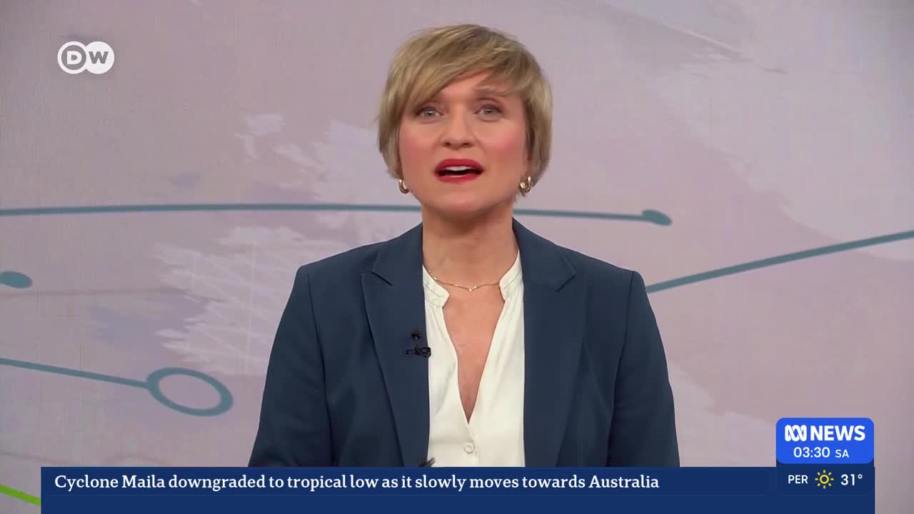 A woman in a dark blue blazer and white shirt speaks directly to me. A news ticker at the bottom of the screen reports Cyclone Maila is downgrading as it moves towards Australia.