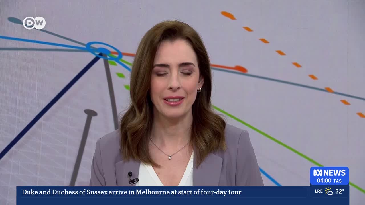 A woman in a grey blazer speaks, her eyes focused just past the camera. A ticker at the bottom of the screen announces the Duke and Duchess of Sussex's arrival in Melbourne for a four-day tour.