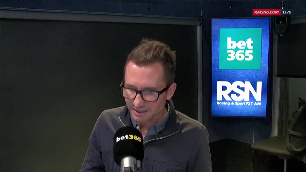 A man with glasses speaks into a microphone, the bet365 logo visible on it. Behind him, a sign displays the RSN Racing & Sport logo, and the Racing.com live stream.
