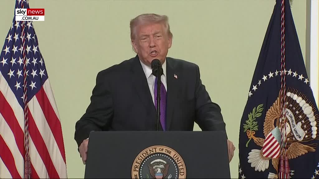 Donald Trump stands at a podium, speaking into a microphone. The American flag stands to his left, and the Presidential flag to his right, as seen on Sky News Extra.