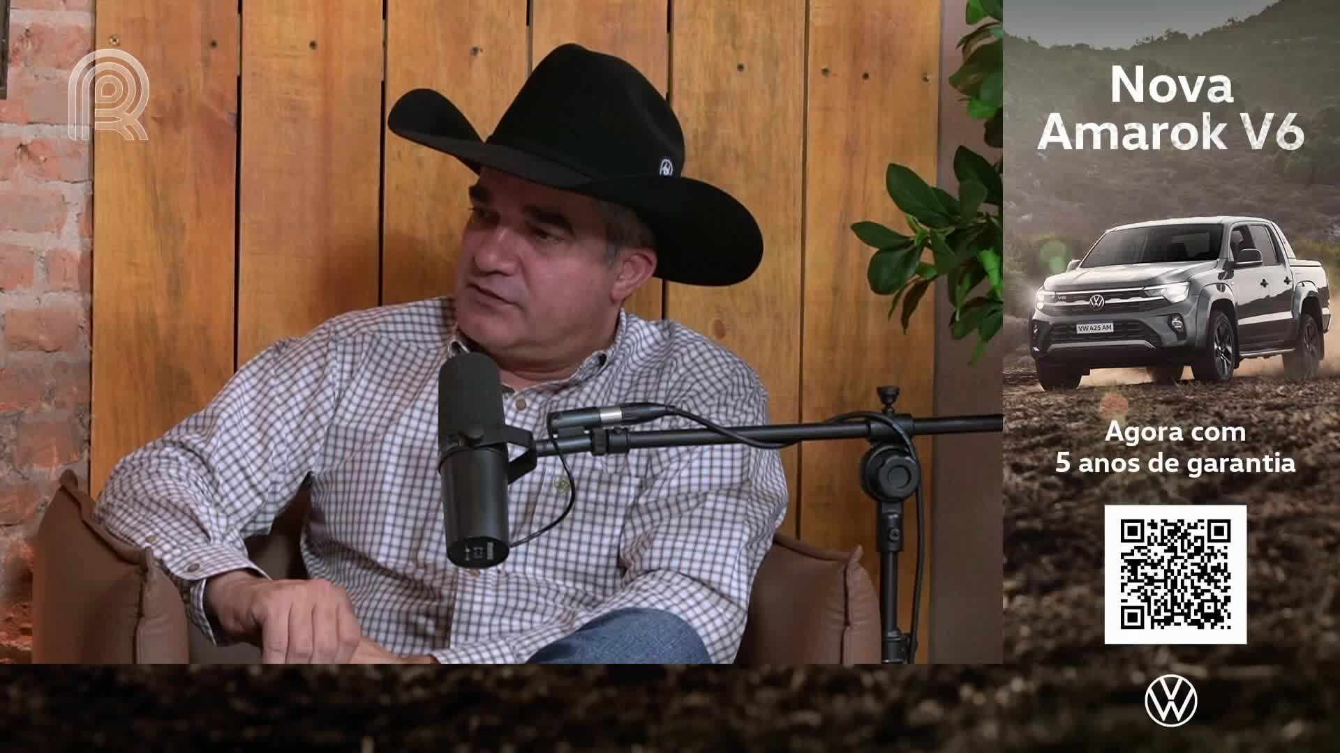 A man in a cowboy hat speaks into a microphone, likely on a Canal Rural broadcast from Brazil. Beside him, an advertisement for a new Volkswagen Amarok pickup truck is displayed.
