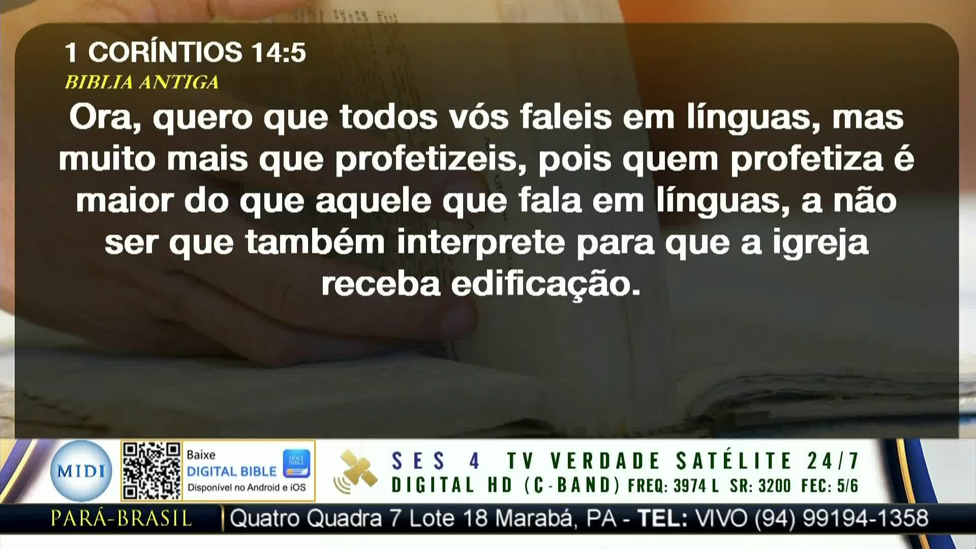 A Bible is open, with text in Portuguese displayed on the screen. Below, the screen shows information about a TV channel, including its frequency and contact details in Pará, Brazil.
