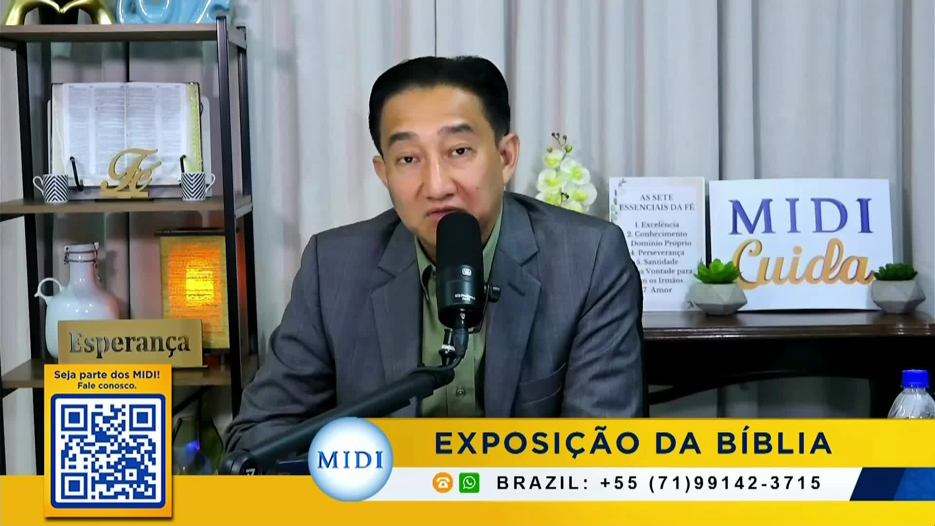 A man in a suit speaks into a microphone, the words "Exposição da Bíblia" displayed below him. A QR code and contact information for Brazil are also visible on the screen.
