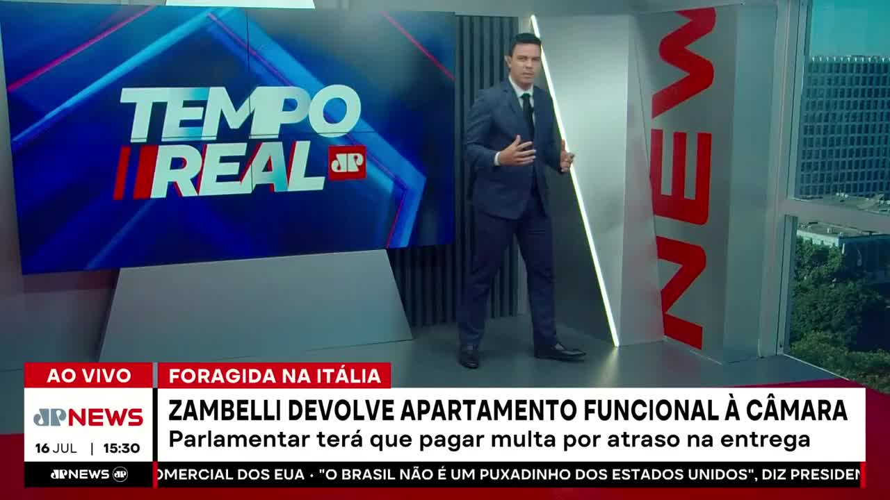 A news anchor from Jovem Pan News in Brazil stands in a studio, gesturing as he speaks. The screen behind him displays "Tempo Real" and breaking news about a politician.
