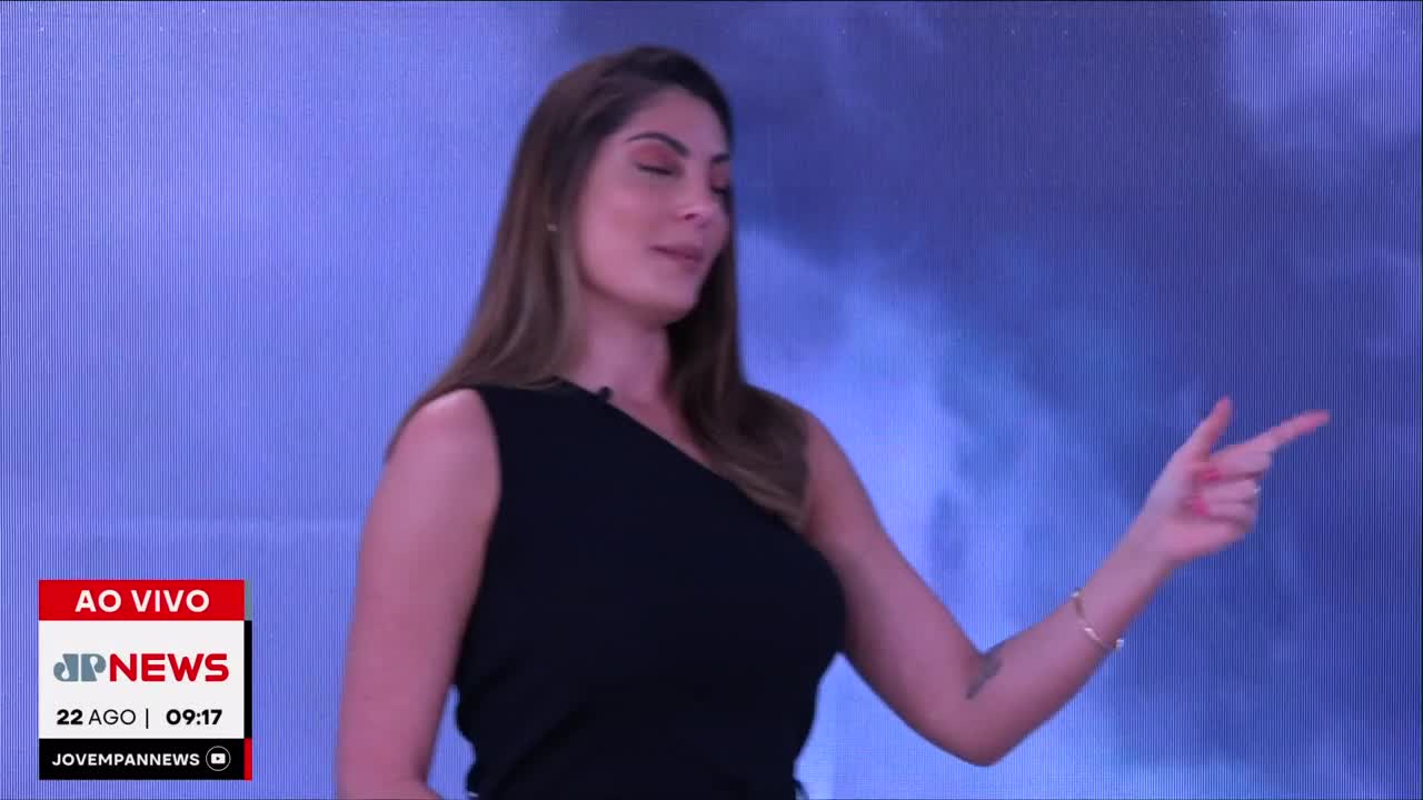 The Jovem Pan News anchor, dressed in black, gestures to her right with a pointed finger, as she speaks. The broadcast is live from Brazil, and the time is 09:17.
