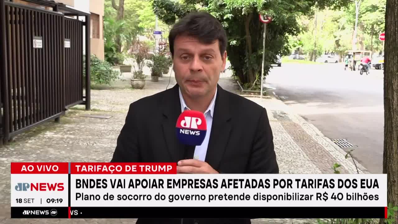 A Jovem Pan News reporter stands outside, microphone in hand, reporting live. Behind him, a street scene unfolds with cars and pedestrians moving slowly in the background.
