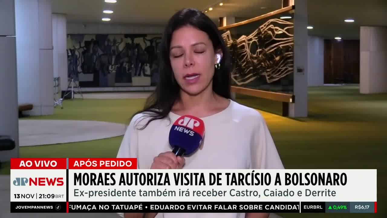 A reporter from Jovem Pan News in Brazil stands in a large, green-carpeted hallway, speaking directly into a microphone. The headline on the screen below announces that Moraes has authorized a visit to Bolsonaro.
