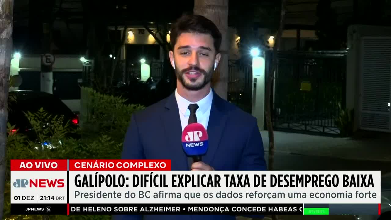 A Jovem Pan News reporter, microphone in hand, speaks directly to the camera from a street in Brazil. Behind him, a car is parked near some shrubbery, and the night sky is visible.
A Jovem Pan News reporter, microphone in hand, speaks directly to the camera from a street in Brazil. Behind him, a car is parked near some shrubbery, and the night sky is visible.