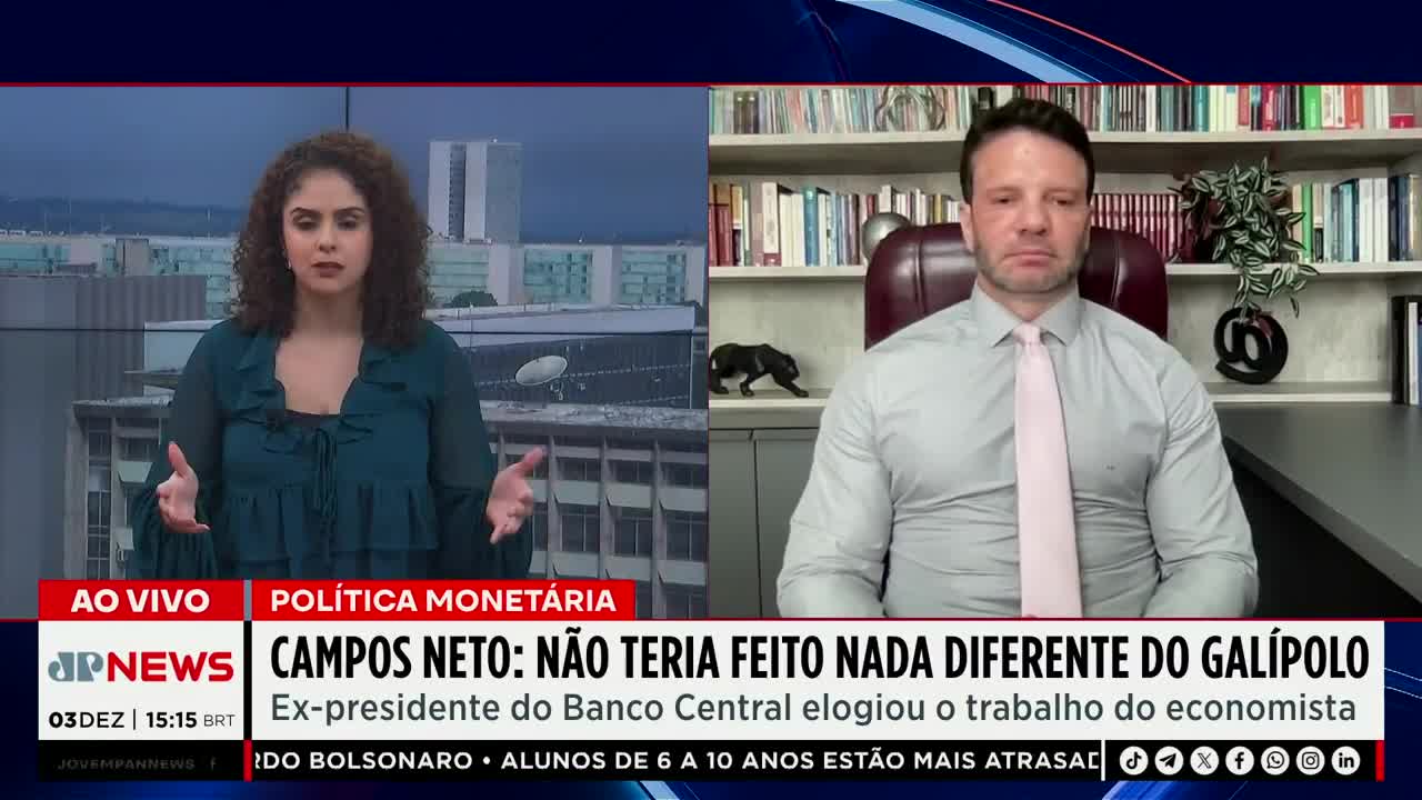 A woman in a teal blouse gestures with both hands as she speaks on Jovem Pan News in Brazil. Across the screen, a man in a light-colored shirt and tie sits in a home office, looking directly at the camera.
A woman in a teal blouse gestures with both hands as she speaks on Jovem Pan News in Brazil. Across the screen, a man in a light-colored shirt and tie sits in a home office, looking directly at the camera.