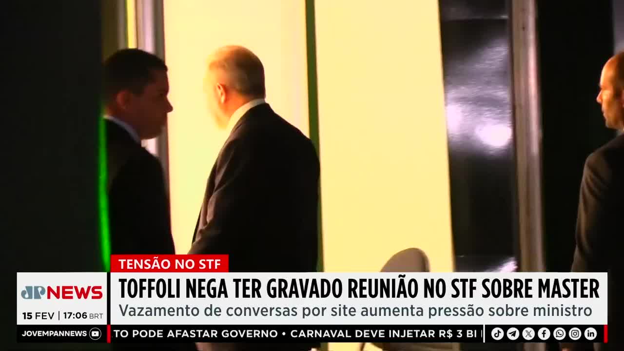 Men in dark suits walk past a bright, yellow wall. A news ticker from Jovem Pan News scrolls across the bottom of the screen, reporting on tensions at the STF. Men in dark suits walk past a bright, yellow wall. A news ticker from Jovem Pan News scrolls across the bottom of the screen, reporting on tensions at the STF.