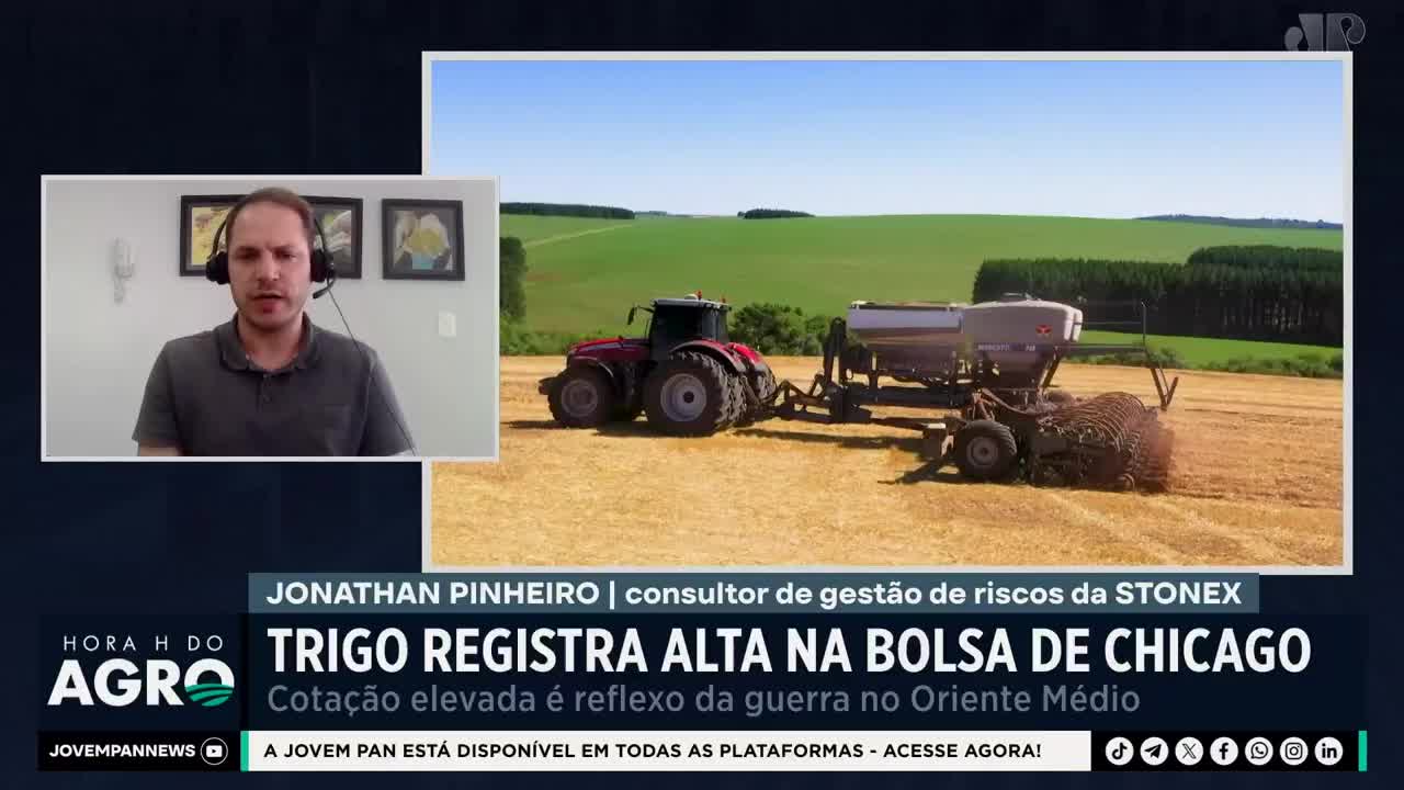 A red tractor pulls a planter across a dry, golden field under a bright blue sky. The Jovem Pan News logo is visible, indicating this segment is from Brazil.