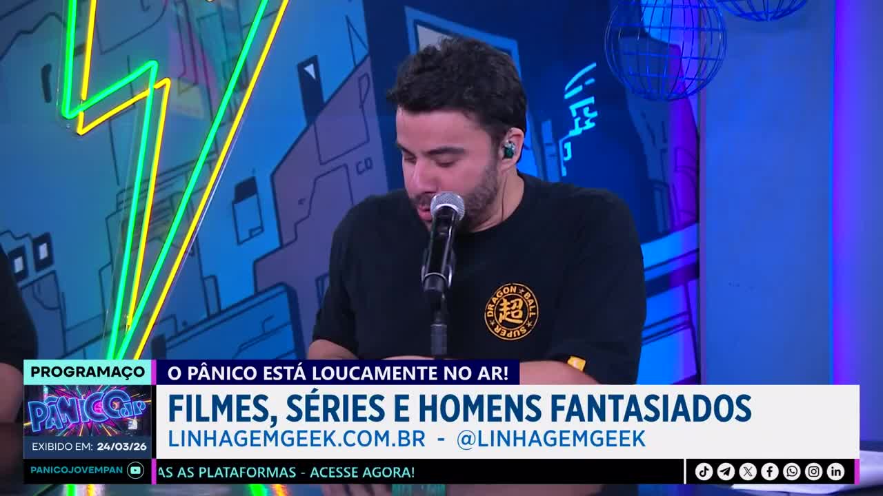 A man speaks into a microphone, his dark shirt featuring a Dragon Ball Z logo. Behind him, neon green and yellow lightning bolts streak across a blue, graphic backdrop. A man speaks into a microphone, his dark shirt featuring a Dragon Ball Z logo. Behind him, neon green and yellow lightning bolts streak across a blue, graphic backdrop.