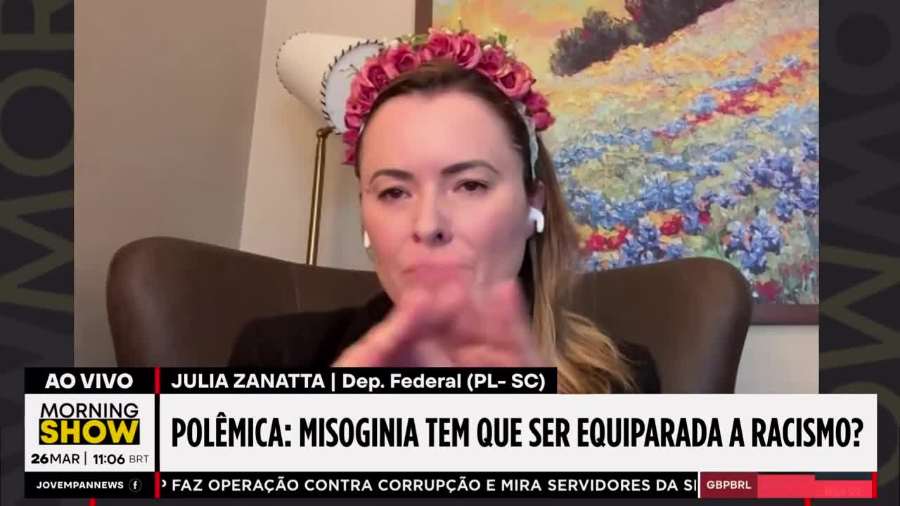 A woman wearing a floral headband speaks animatedly, her hands gesturing. The Jovem Pan News logo and a headline about misogyny appear on screen. A woman wearing a floral headband speaks animatedly, her hands gesturing. The Jovem Pan News logo and a headline about misogyny appear on screen.