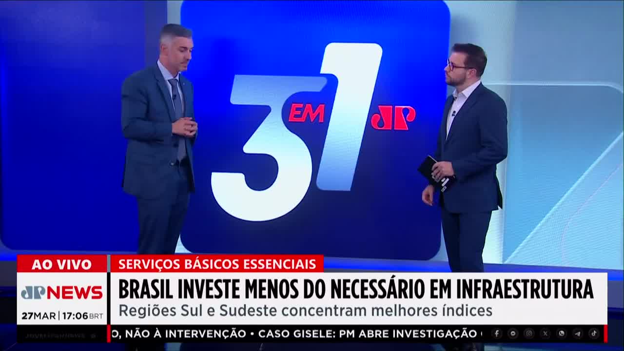 Two men in suits stand on a brightly lit studio set, a large blue graphic with the number "31" behind them. A news ticker scrolls across the bottom of the screen, displaying headlines from Jovem Pan News. Two men in suits stand on a brightly lit studio set, a large blue graphic with the number "31" behind them. A news ticker scrolls across the bottom of the screen, displaying headlines from Jovem Pan News.