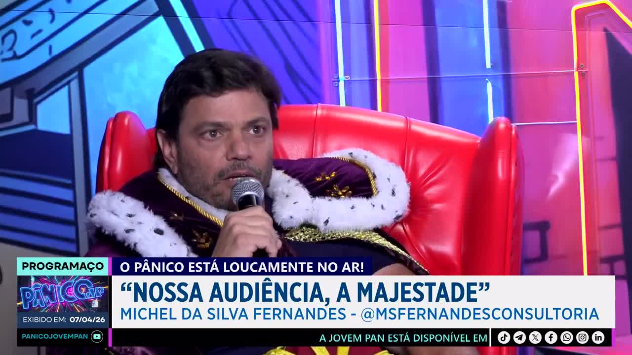 A man wearing a regal robe and crown sits in a plush red chair, holding a microphone. He speaks into it, his expression serious, as a Jovem Pan News graphic displays his name and a quote about the audience.