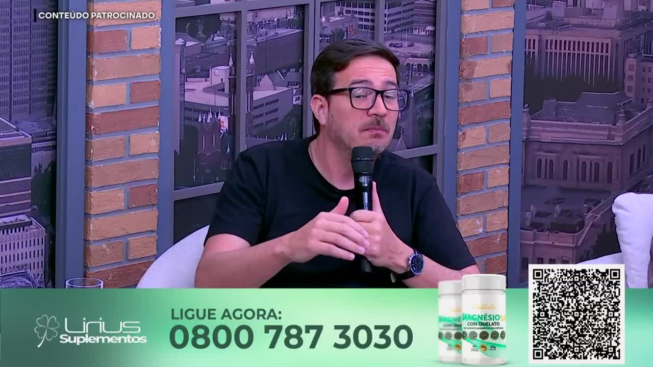 A man with glasses speaks into a microphone on a set that looks like it's for Jovem Pan News. Below him, an advertisement for Lirius Suplementos displays a phone number and a QR code.