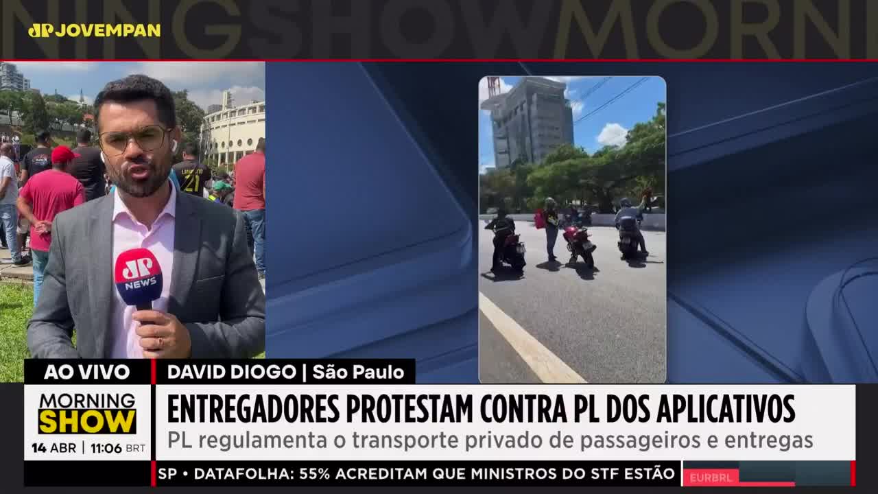Motorcyclists are gathered on a street in São Paulo, some with their hands raised. A reporter from Jovem Pan News stands nearby, microphone in hand.