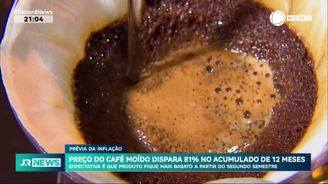 Hot coffee is pouring into a paper filter, creating a foamy, dark brown brew. The Record News graphic at the bottom of the screen reports on the rising cost of ground coffee in Brazil.
