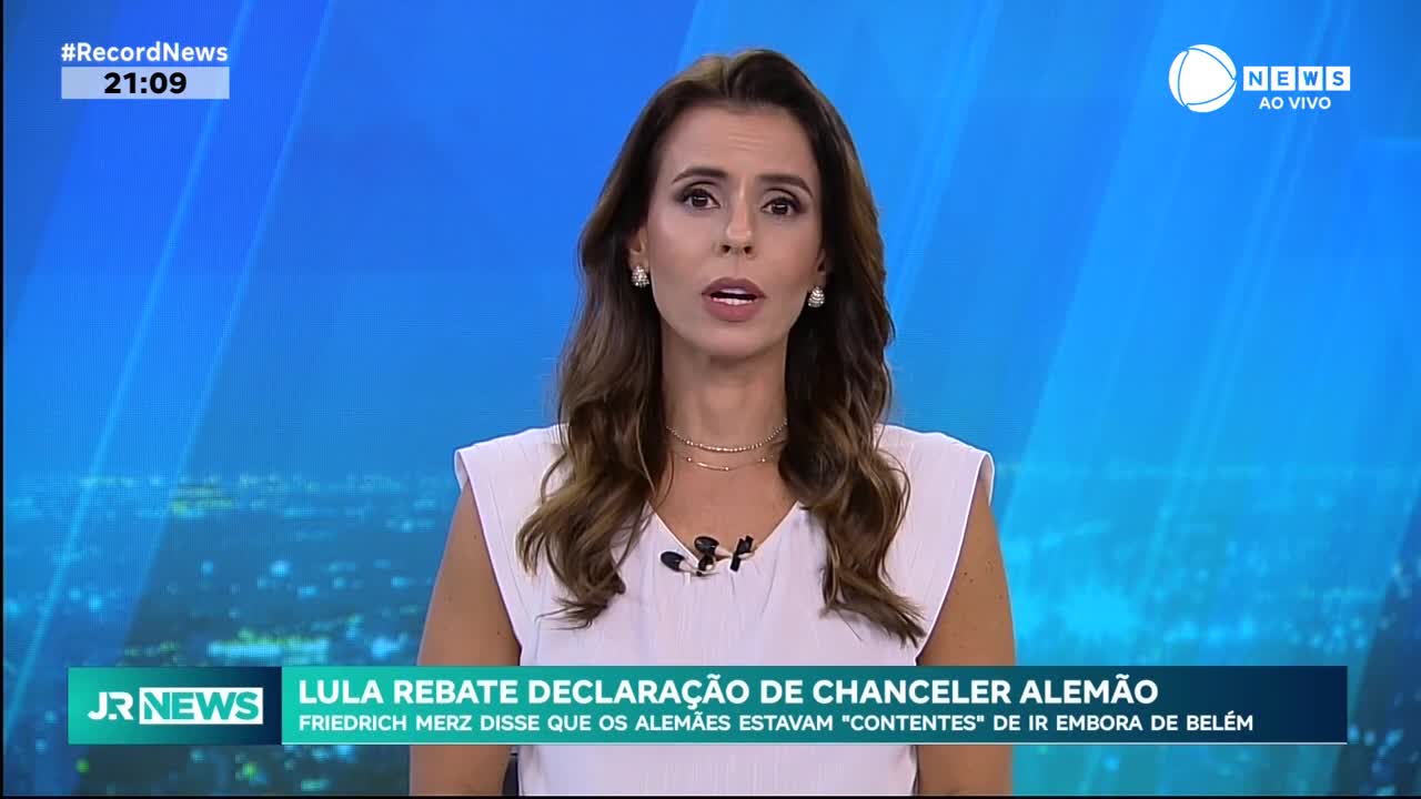 The anchor on Record News in Brazil is speaking directly to the camera, her expression serious. Below her, the headline discusses a debate about a German chancellor's statement.
