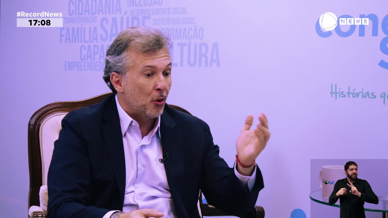 A man in a dark suit gestures with his right hand while speaking. The Record News chyron indicates the time is 17:08.