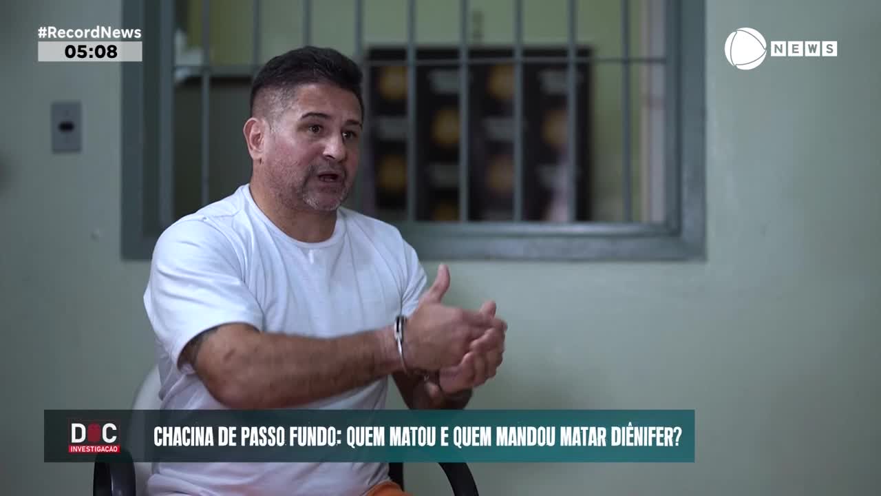 A man in a white t-shirt, handcuffed, gestures with his hands as he speaks. The Record News logo appears in the corner, indicating this is a broadcast from Brazil.