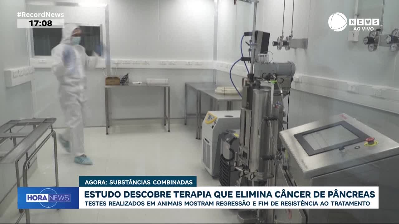 A person in a full white hazmat suit walks across the sterile laboratory. Complex scientific equipment stands ready for use.