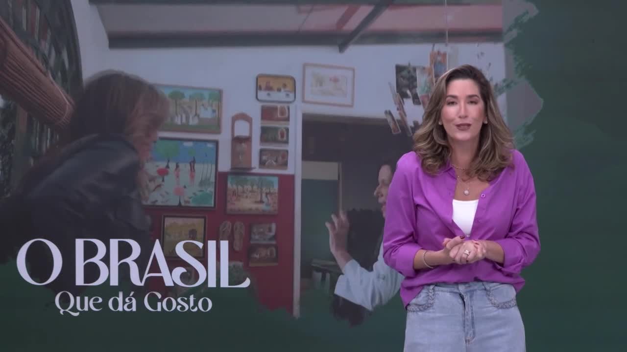 A woman stands in front of a screen displaying "O Brasil Que Dá Gosto" with images of Brazilian art. She speaks with her hands clasped, wearing a bright purple shirt and denim skirt.
