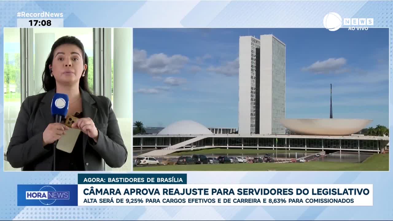A reporter holds a phone as she speaks in front of the National Congress building in Brasília. The screen displays "Record News" and the time 17:08.