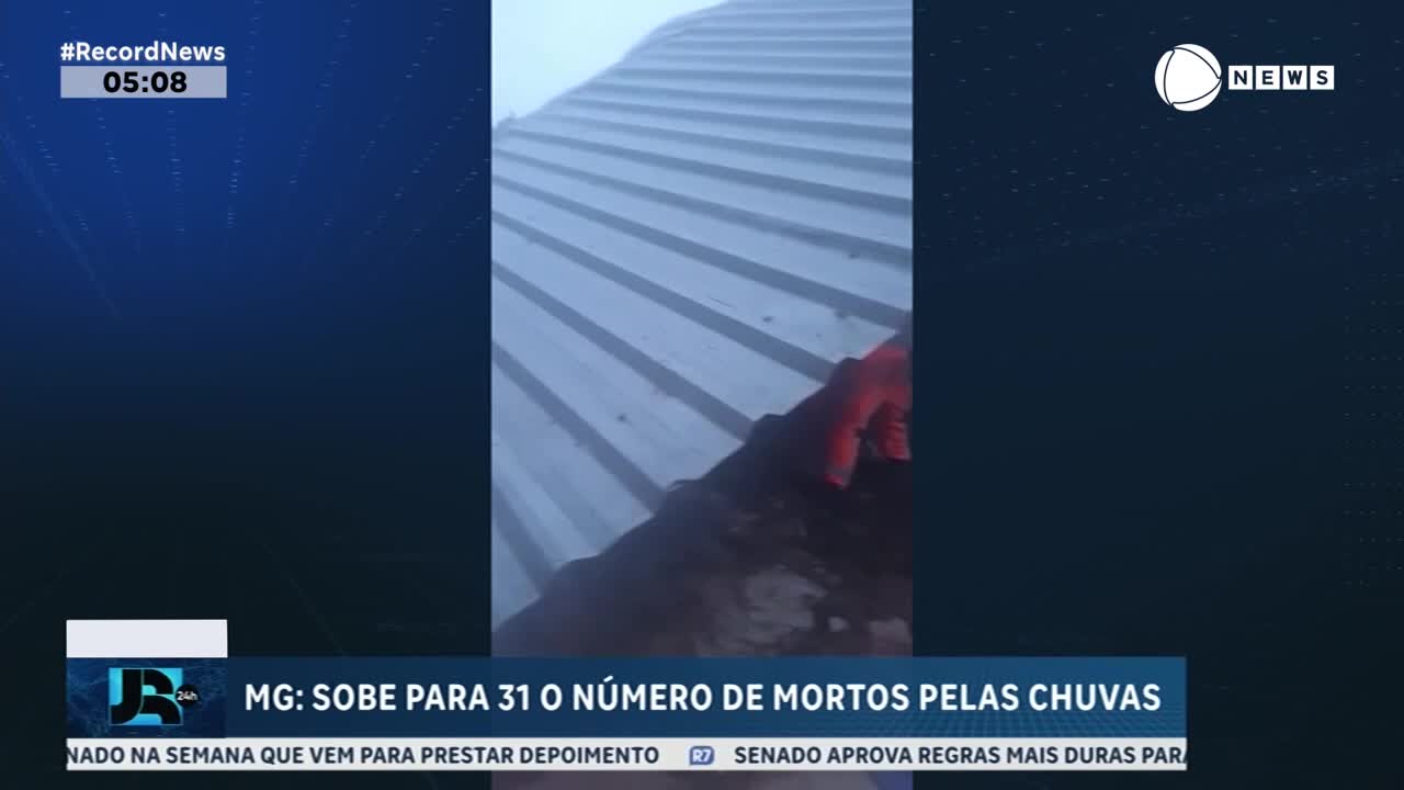 A gloved hand grips the edge of a corrugated metal roof, slick with rain. Record News reports that the number of deaths from the rains in Minas Gerais has risen to 31.