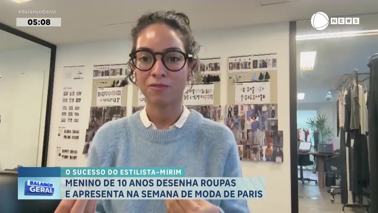 A young woman with glasses speaks directly to the camera, a wall covered in fashion sketches behind her. The Record News logo appears in the corner, indicating a broadcast from Brazil.