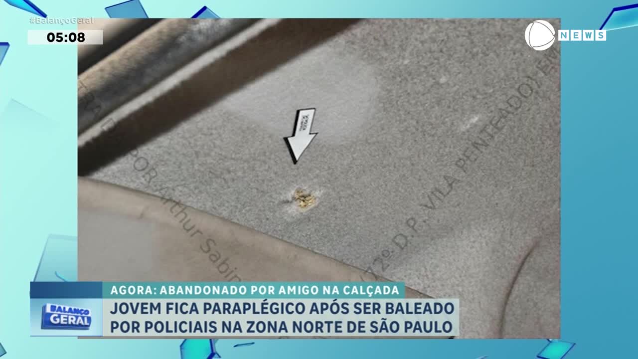A white arrow points to a small, discolored mark on a textured surface. Text on the screen from Record News in Brazil reports a young man became paralyzed after being shot by police.