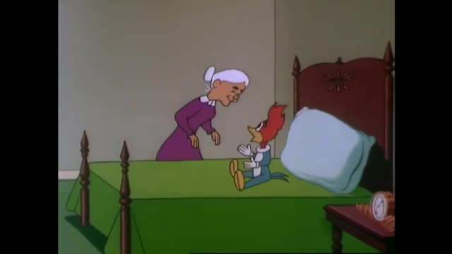 A cartoon woodpecker sits on a bed, hands clasped, looking up at a smiling woman. She leans toward him, her expression gentle as she seems to address the bird.
