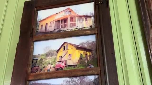 Three pictures of weathered buildings are framed together in a wooden door. The top image shows a house with a porch, while the others display a yellow building with a truck and tractor nearby.
