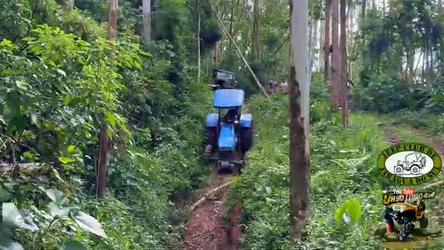 A bright blue tractor churns up the dirt track, heading deeper into the dense Brazilian forest.  A few people are visible further up the trail, watching the procession.