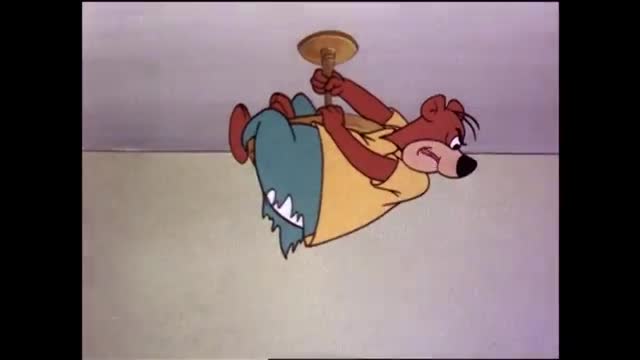 A brown bear in a yellow shirt dangles precariously from a ceiling fixture, his legs tangled in a blue cloth. He looks down with a worried expression, as if he's just realized his predicament.