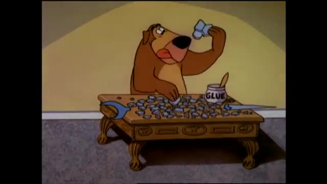 A brown dog, looking a bit overwhelmed, is carefully placing small, blue objects onto a table covered with more of them. A jar of glue sits nearby, its contents ready for use.