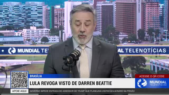 A man in a suit speaks into a microphone, his words broadcast live from Brasília. Behind him, the cityscape of Brazil's capital unfolds on a large screen.