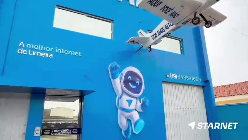 A cartoon astronaut with a wide smile dances on the bright blue wall. Above him, a small white airplane hangs, its wings angled as if in flight.