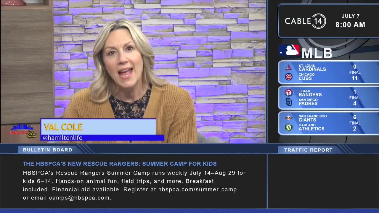 Val Cole from Cable 14 Hamilton is speaking directly to the camera. Scores from MLB games flash on the screen beside her, and a bulletin board lists information about a summer camp.
