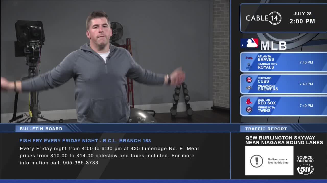 The man in the grey hoodie is stretching, arms out to the sides, as if he's about to begin an exercise routine. Cable 14 in Hamilton is showing the MLB scores and a traffic report on the right side of the screen.
