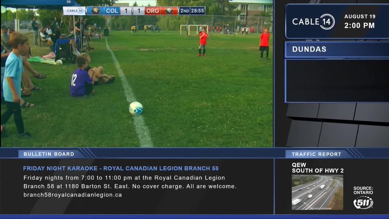 A soccer ball sits near the sideline, while kids in red jerseys wait on the field. Cable 14 Hamilton is broadcasting a game from Dundas.
