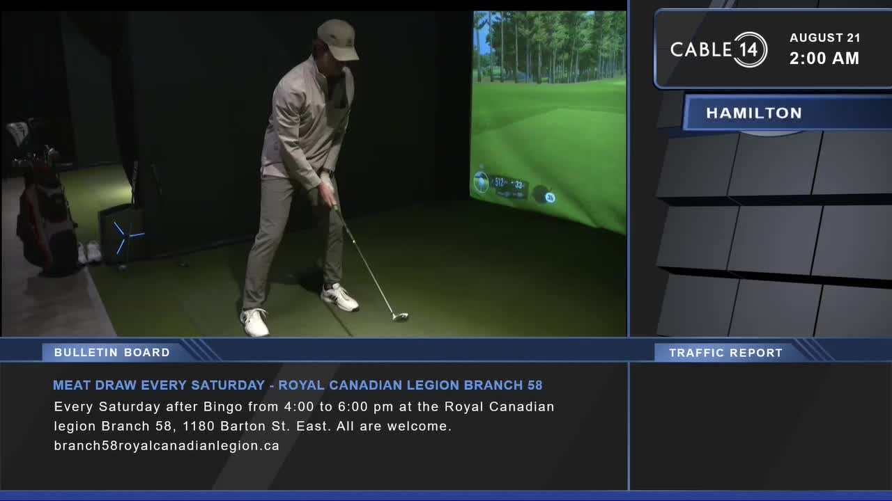 A man in a cap and grey pants is mid-swing, poised over a golf ball. The Cable 14 Hamilton screen shows a virtual golf course in the background.
