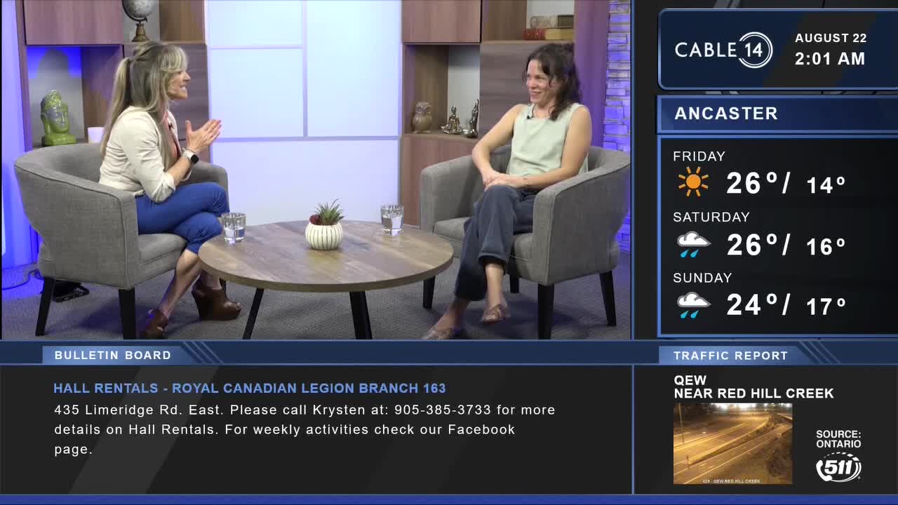 Two women sit in armchairs, engaged in conversation on Cable 14 Hamilton. The weather forecast for Ancaster is displayed beside them, with temperatures in the mid-twenties.
