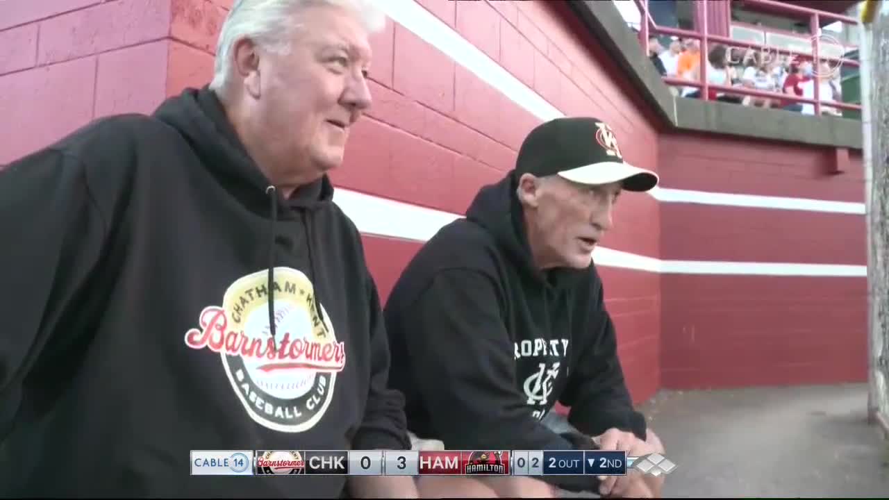 Two men in black hoodies sit side-by-side, watching the game on Cable 14. The score shows Chatham-Kent Barnstormers trailing Hamilton.
