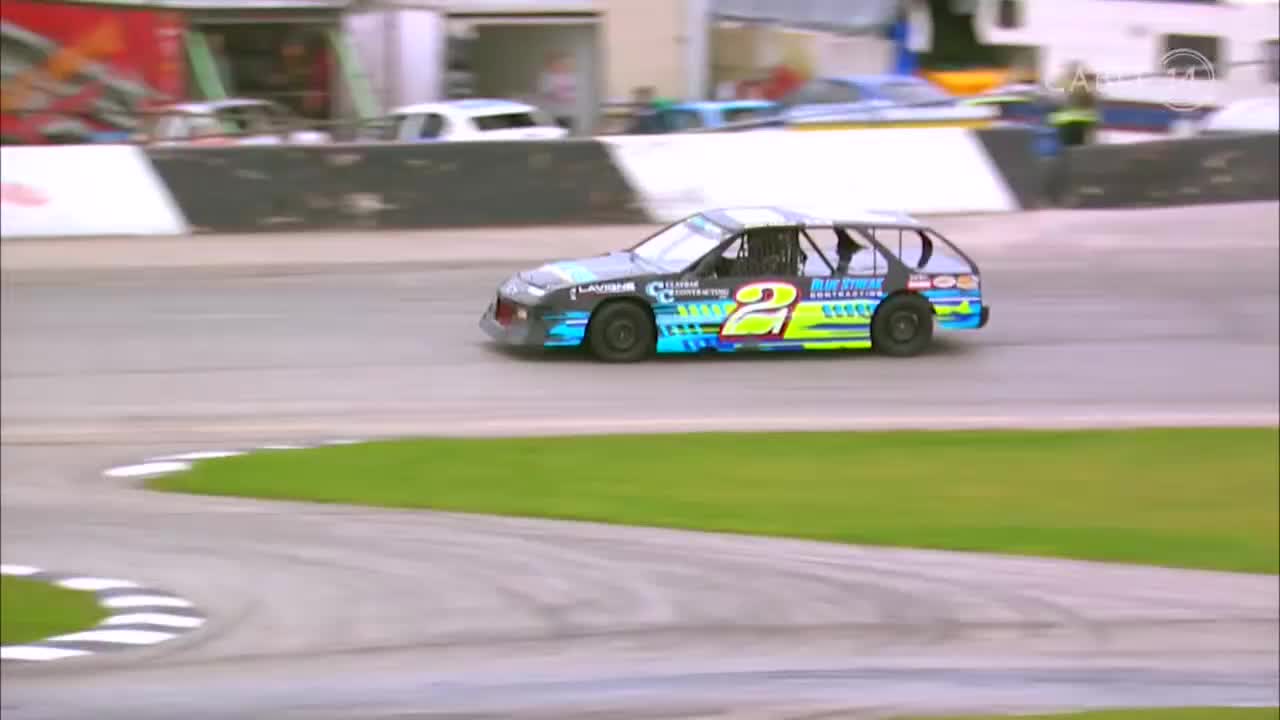 The number 2 car, painted with blue and yellow accents, rounds the turn. It's a Cable 14 Hamilton race, and the car is hugging the inside line.
